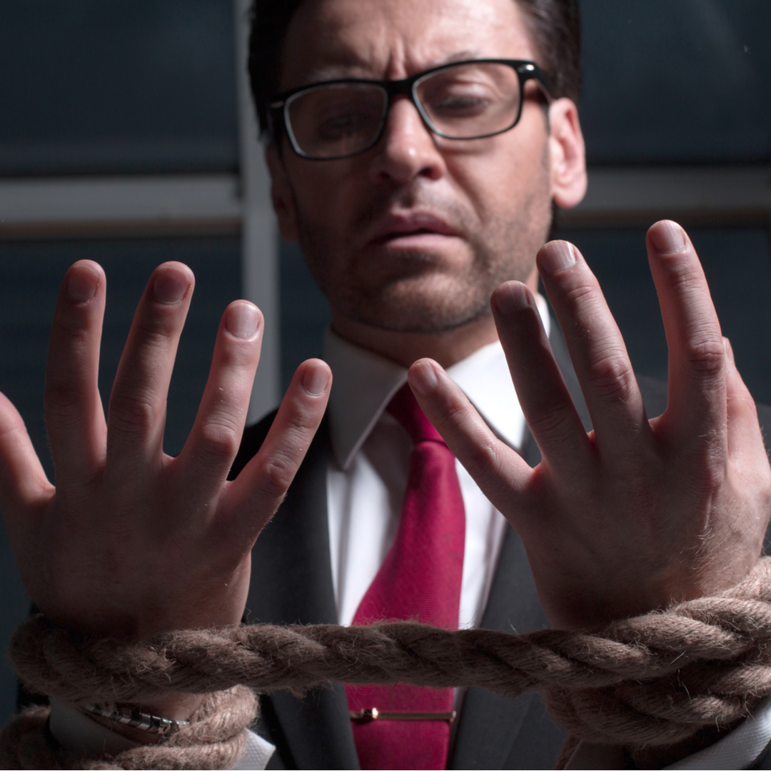 Businessman in dark suit and red tie as hostage hands tied by thick hemp rope